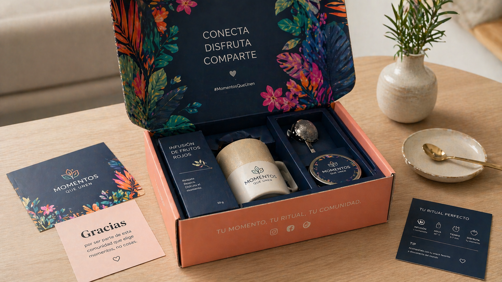 Caja de experiencia de marca tipo unboxing con diseño colorido y contenido organizado, incluyendo infusión, taza y accesorios, acompañada de tarjetas impresas sobre mesa de madera. Cajas de Suscripción.