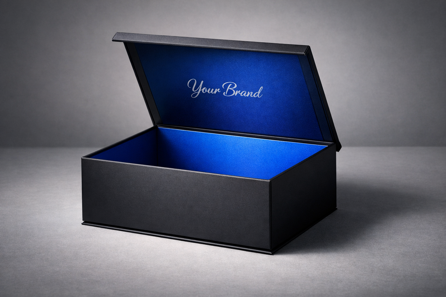 Caja rígida premium negra con interior azul intenso y tapa abierta, diseño minimalista y elegante para empaque de lujo personalizado. El "Unboxing" Perfecto